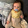 Gianni is registered to the contest to win money with this photo: baby, pacifier, blanket, couch, bib, striped_onesie, infant, child, face, hand, lying_down, cozy, soft_texture, comfort, indoors, young_child, cute, portrait, expression, relaxed