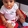 baby, pacifier, white_shirt, shorts, red_lobsters, red_blanket, spider_web_pattern, blue_socks, cute, chubby_legs, sitting, indoors, child, infant, smiling_text, curly_hair, large_eyes, comfortable, cozy, playpen