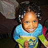 beaded_hair, blue_shirt, braids, candid, child, colorful_clothing, couch, face, flash_photography, furniture, girl, green_sleeves, happy, home, indoors, playful, portrait, sitting, smiling, toddler