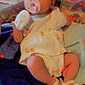 baby, infant, pacifier, headband, bow, mittens, sandals, white_outfit, tattooed_arm, bed, blanket, colorful, red_hearts, cute, child, portrait, indoors, soft_lighting, lying_down, cozy