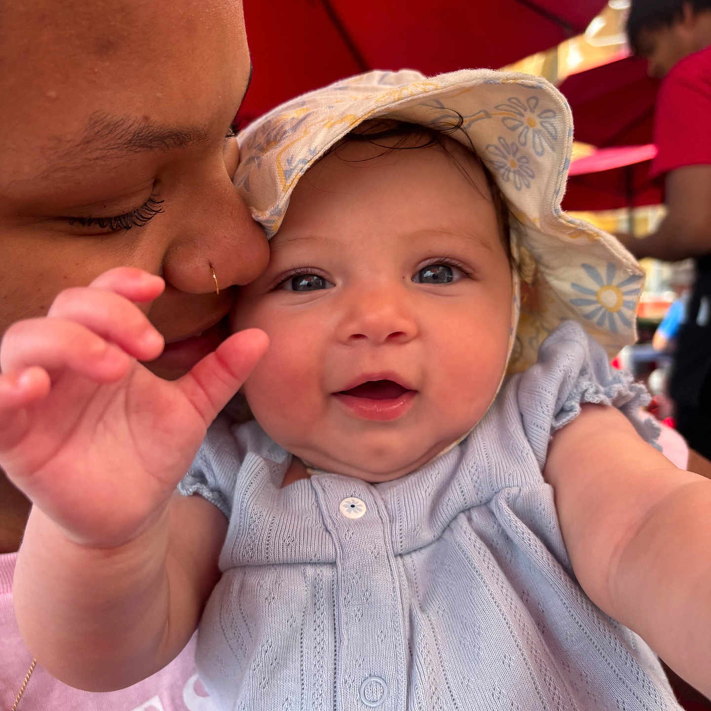 Milani is registered to the contest to win money with this photo: baby, child, person, adult, hat, smile, face, closeup, outdoor, umbrella, red, clothing, happy, love, nuzzle, skin, portrait, hand, cute, tender