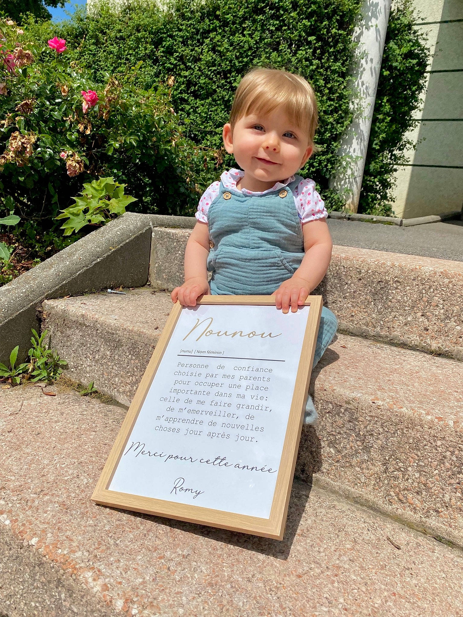 Romy a rejoint le concours — aidez-le/la à gagner de superbes lots ! baby_toddler_clothing, child, dress, flower, font, fun, grass, handwriting, happy, joy, leisure, people_in_nature, person, plant, public_space, recreation, shrub, sitting, smile, t_shirt