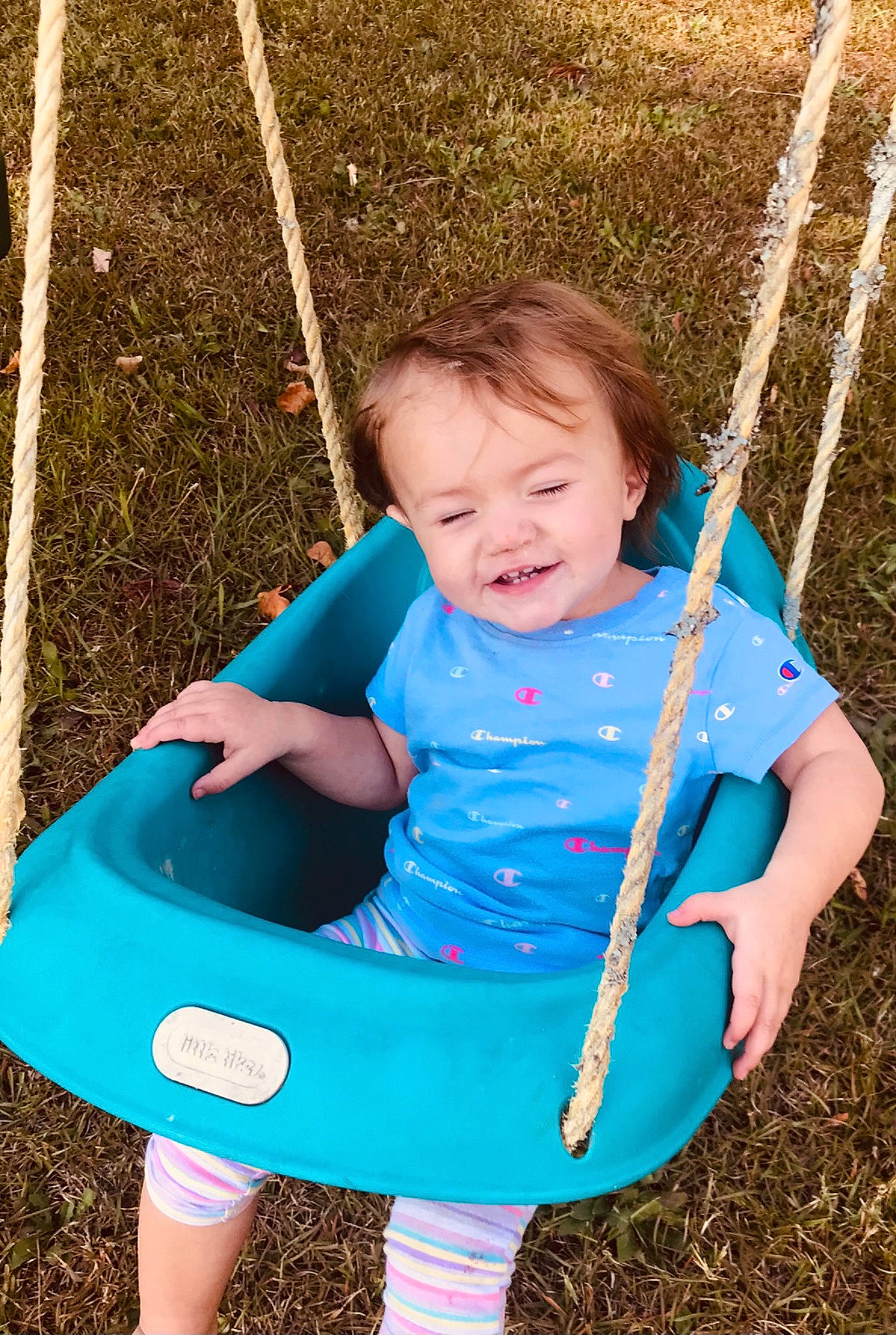 Olivia joined the competition — help win amazing prizes! baby, blue, face, fun, grass, happy, leaf, leisure, people_in_nature, person, photograph, plant, recreation, skin, smile, summer, swing, toddler, tree, white