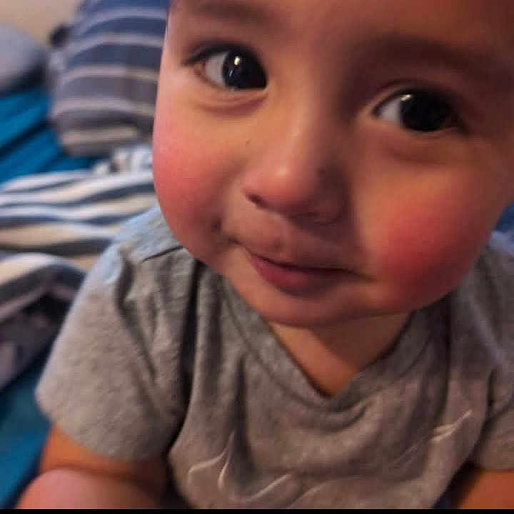 Tre'Von Gibbons Jr is registered to the contest to win money with this photo: child, baby, face, rosy_cheeks, gray_shirt, curious_eyes, portrait, indoor, candid, young_child, person, close_up, smile, cute, head, skin, expression, toddler, striped_blanket, background