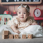Emma participe au concours pour gagner de l'argent avec cette photo : baby, infant, child, headband, wooden_blocks, blanket, table, face, smile, eyes, hand, toy, decor, clock, pencils, colorful, cute, portrait, indoor, soft_lighting