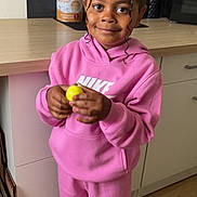 Mya a rejoint le concours — aidez-le/la à gagner de superbes lots ! child, pink_tracksuit, nike, yellow_ball, kitchen, smile, curly_hair, indoor, flooring, cabinet, countertop, paper_towel, map, poster, appliance, person, standing, casual_clothing, happy, young