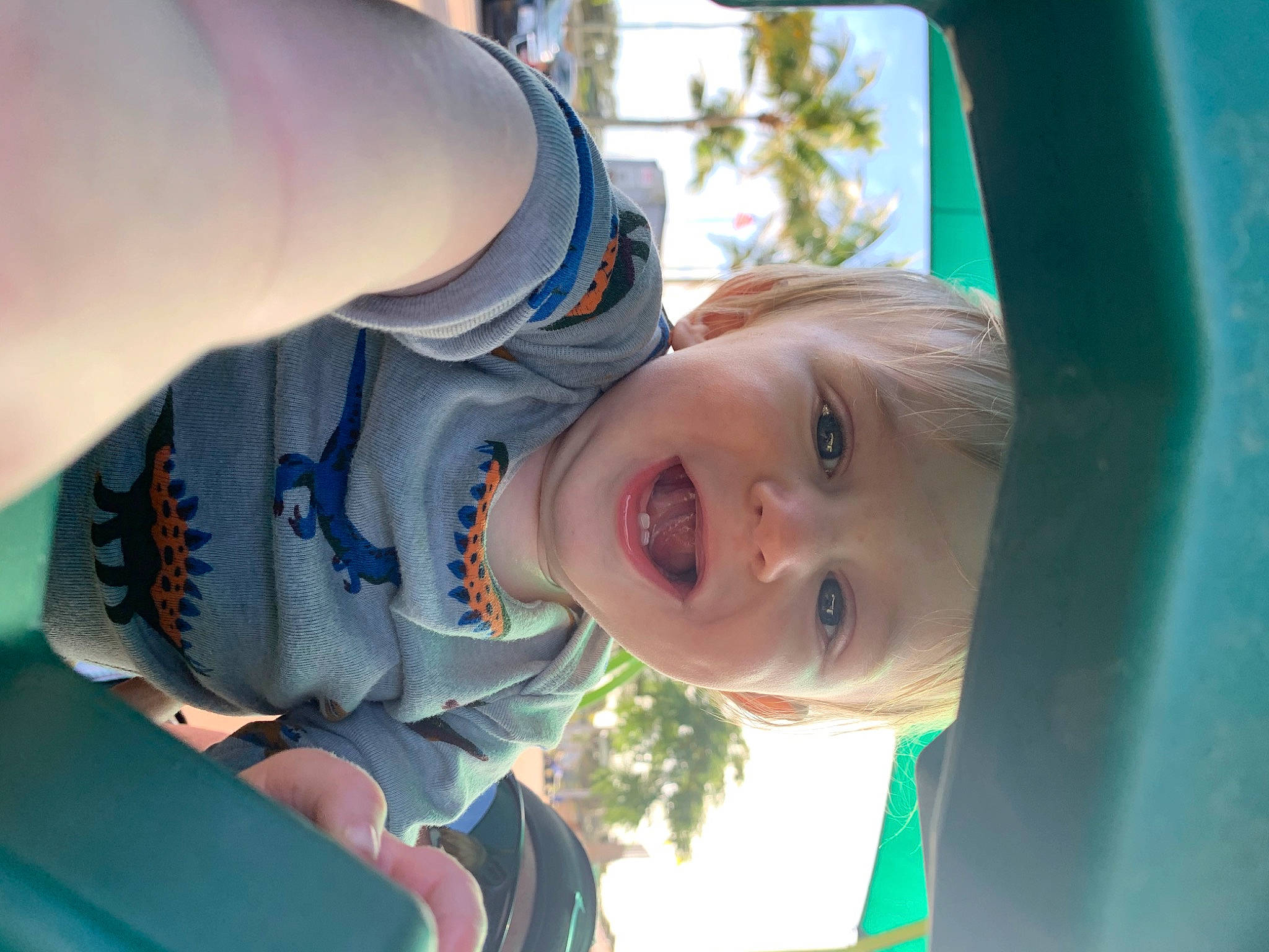 Theodore is registered to the contest to win money with this photo: baby, baby_toddler_clothing, child, elbow, electric_blue, finger, fun, gesture, grass, happy, laugh, leisure, outdoor_play_equipment, person, recreation, sitting, smile, thumb, toddler, tree