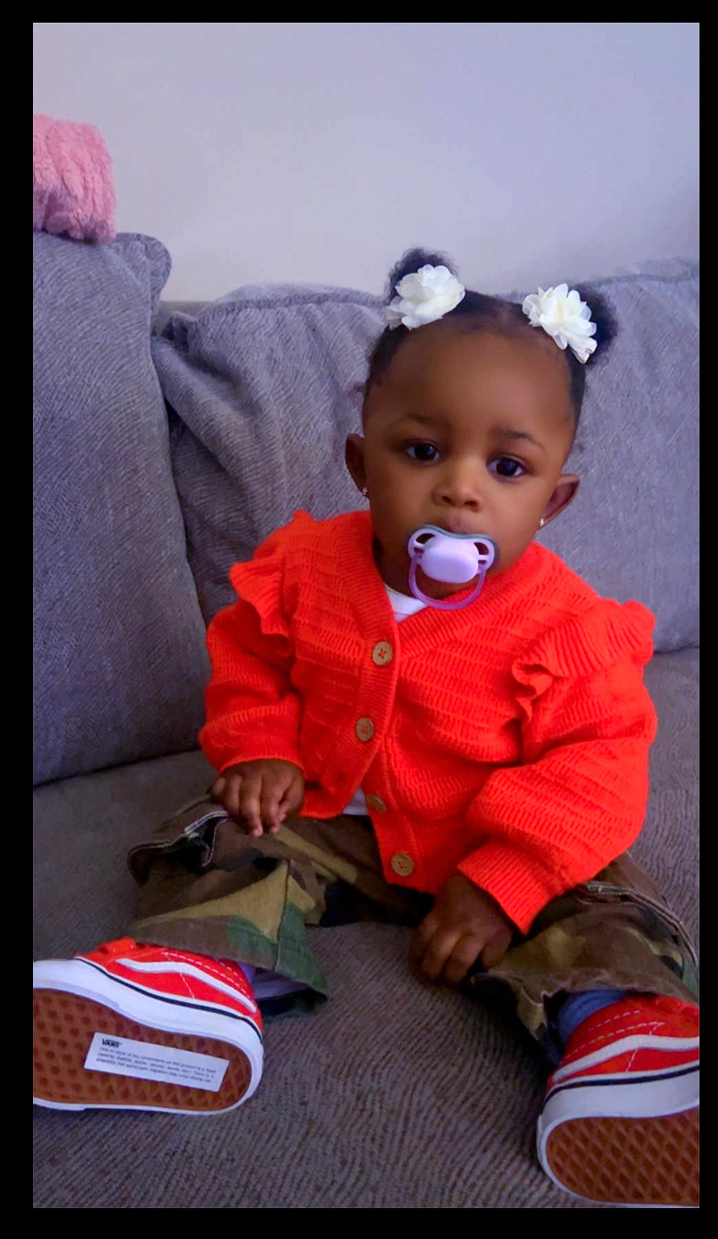 Nevaeha joined the competition — help win amazing prizes! toddler, child, pacifier, orange_sweater, camouflage_pants, red_shoes, flower_hair_accessories, couch, gray_couch, indoors, cute, sitting, young_child, baby, fashion, portrait, casual_clothing, cozy, home, person