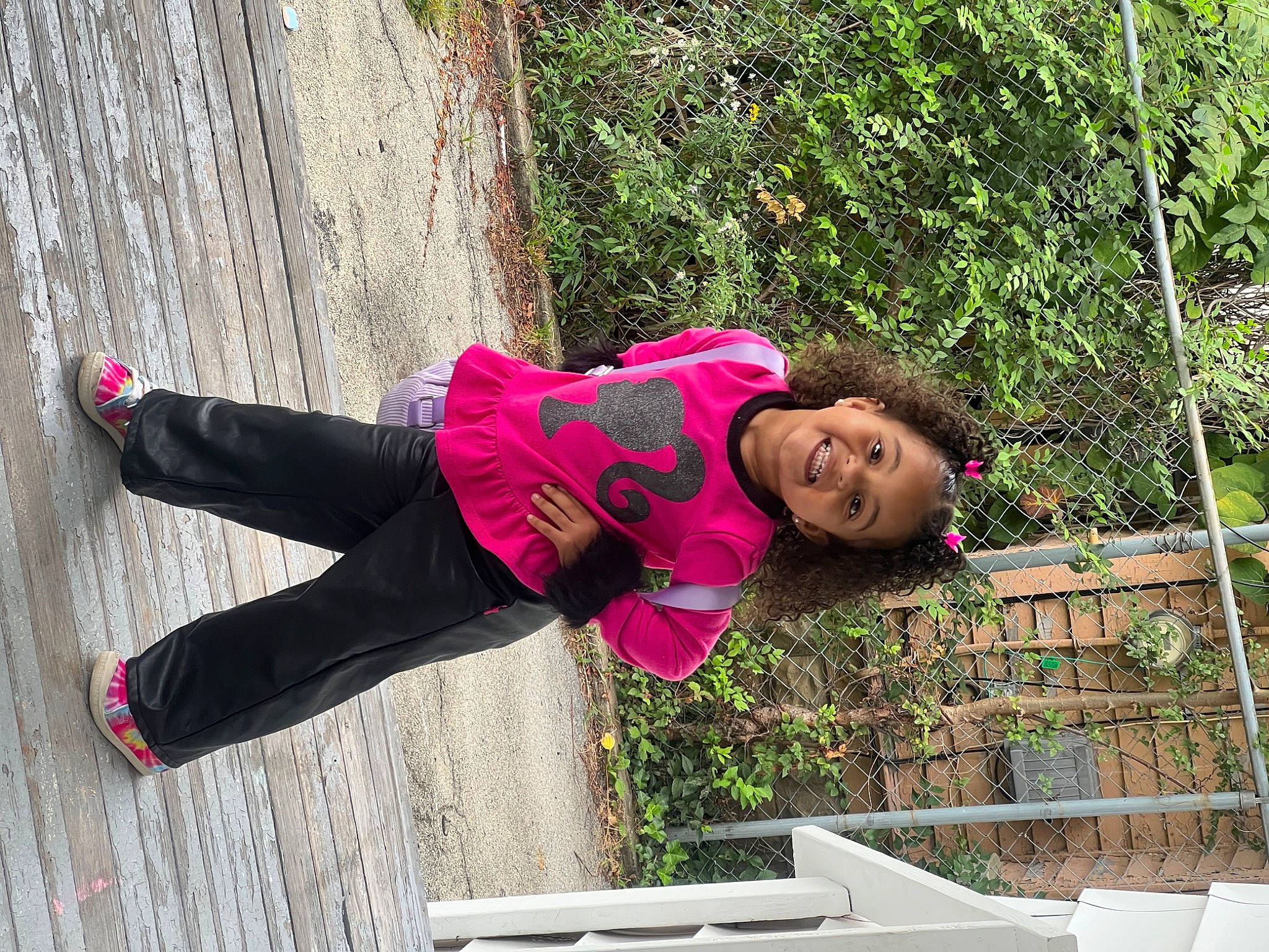 Maleah is registered to the contest to win money with this photo: active_pants, carmine, fun, happy, hat, human_leg, jacket, joy, leisure, magenta, outdoor_shoe, person, pink, plant, recreation, smile, sweatpant, thigh, toddler, tree
