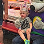 Axton joined the competition — help win amazing prizes! bench, celebration, child, colorful, costume, curly_hair, event, fun, happy, indoor, mascot, party, party_hat, people, person, shorts, smile, socks, table, tshirt