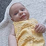 baby, smiling, yellow_outfit, towel, carpet, infant, face, hand, cute, lying_down, indoors, child, portrait, soft_texture, buttoned_clothing, happy, skin, expression, small_fingers, casual