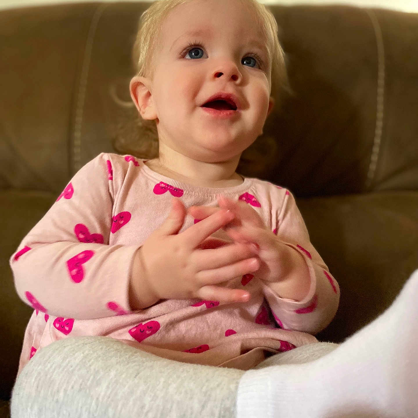 Hazel Adkins joined the competition — help win amazing prizes! blue_eyes, brown_couch, casual_clothing, child, clapping_hands, cozy, cute, gray_pants, happy, heart_pattern, home, indoor, pink_shirt, portrait, sitting, smiling, soft_lighting, toddler, white_socks, young_child