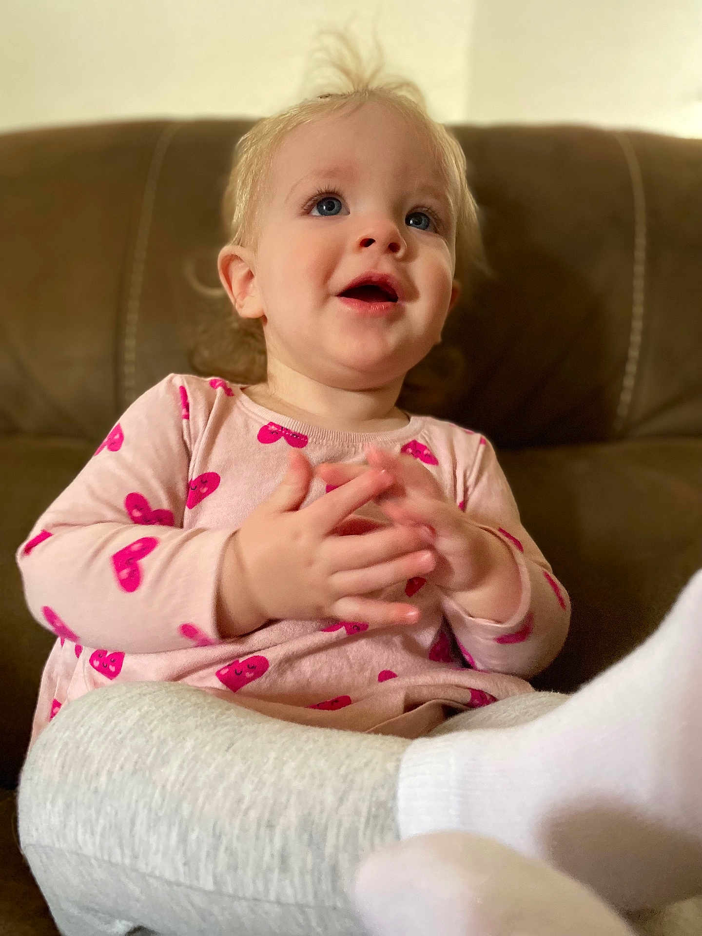 Hazel Adkins joined the competition — help win amazing prizes! toddler, child, blue_eyes, pink_shirt, heart_pattern, clapping_hands, brown_couch, soft_lighting, indoor, smiling, cute, sitting, cozy, casual_clothing, white_socks, gray_pants, portrait, happy, young_child, home
