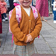 Agathe participe au concours pour gagner de l'argent avec cette photo : backpack, brown_cardigan, casual_clothing, child, crowd, daytime, fashion, girl, gold_shoes, happy, outdoor, people, pigtails, plaid_skirt, sidewalk, smiling, street, urban, white_socks, woman