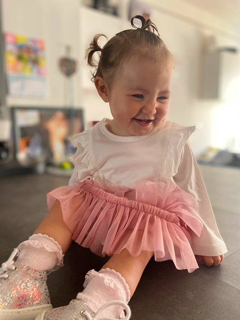 Agathe a rejoint le concours — aidez-le/la à gagner de superbes lots ! baby_toddler_clothing, child, day_dress, dress, embellishment, face, fashion_accessory, fun, happy, human_leg, joy, magenta, person, pink, purple, skin, sleeve, smile, sock, standing