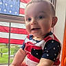 Colter joined the competition — help win amazing prizes! baby, child, smiling, portrait, indoors, window, american_flag, clothing, stars, stripes, red, white, blue, happy, cute, face, person, infant, sitting, natural_light