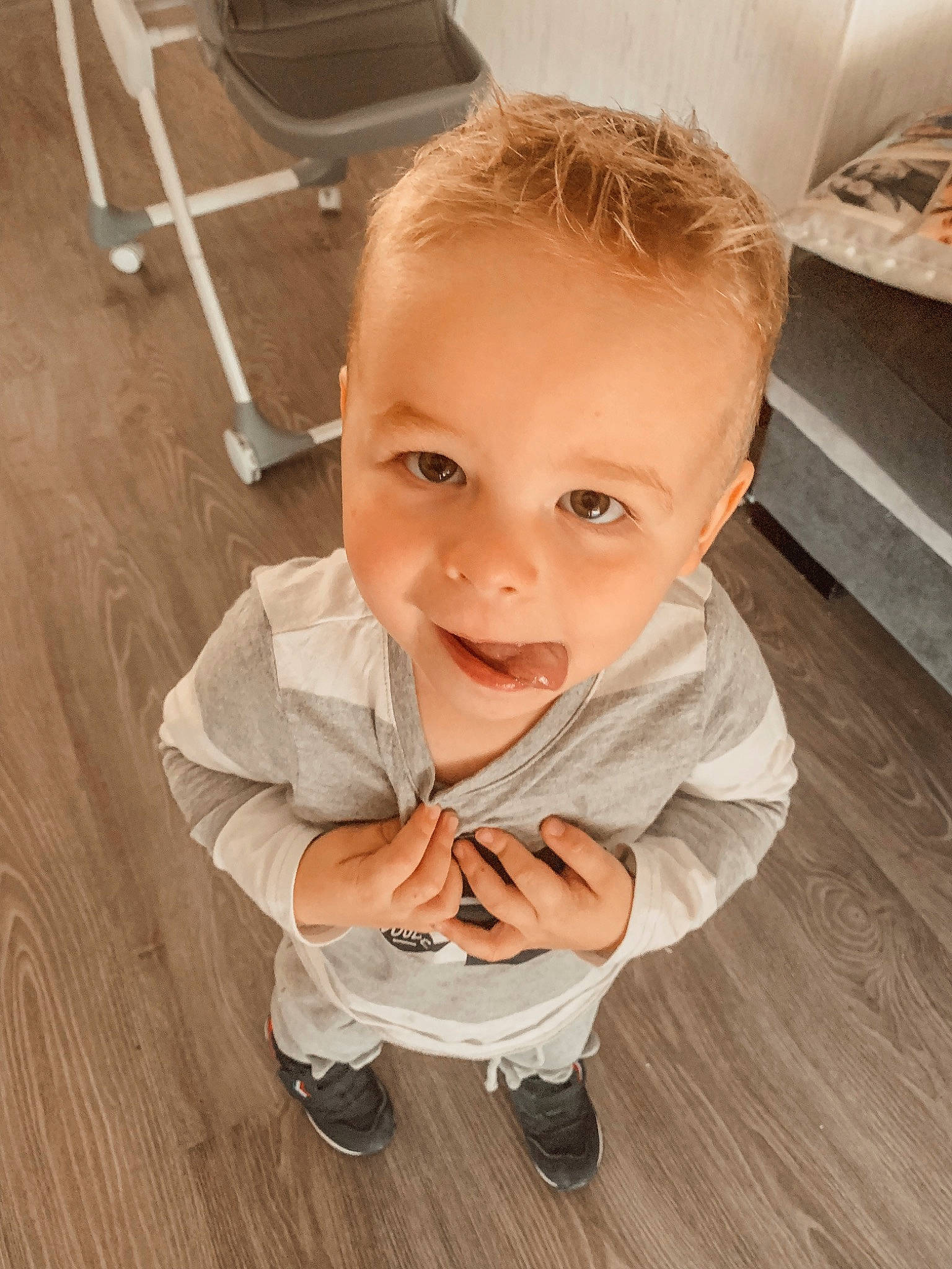Louka a rejoint le concours — aidez-le/la à gagner de superbes lots ! baby, baby_toddler_clothing, chair, cheek, child, eye, floor, flooring, foot, gesture, happy, hardwood, human_leg, person, shoe, skin, smile, standing, thumb, toddler