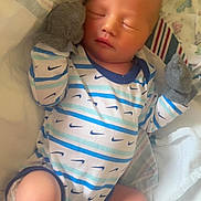 Kaiser is registered to the contest to win money with this photo: baby, newborn, sleeping, onesie, mittens, blanket, infant, soft_lighting, cozy, cute, peaceful, indoor, clothing, human, person, rest, small, legs, hands, face