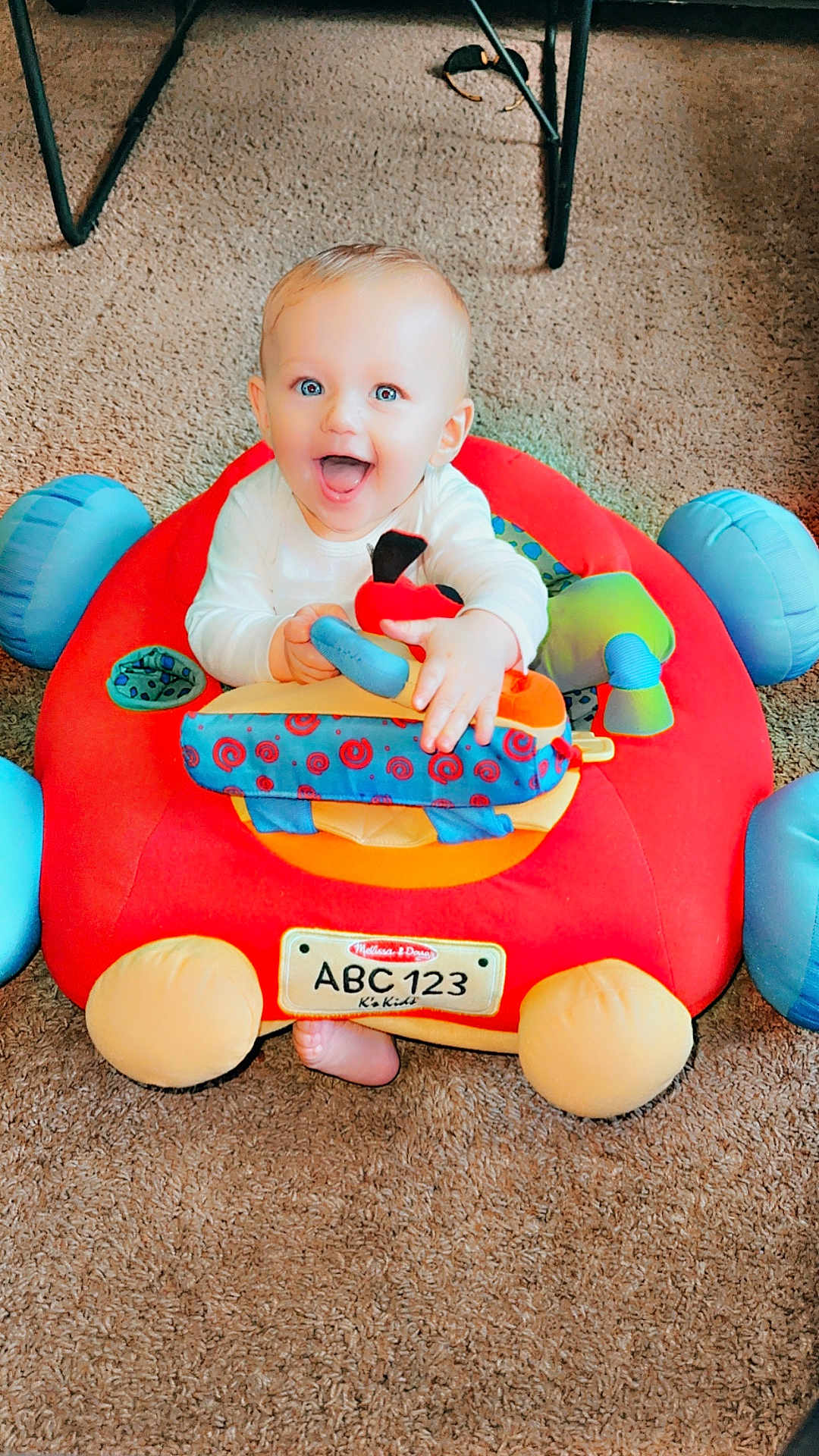 Kaiser joined the competition — help win amazing prizes! baby, child, toy, plush_toy, car_toy, carpet, indoor, smiling, happy, blue_eyes, sitting, playtime, cute, infant, hands, feet, colorful, soft_toy, person, young_child