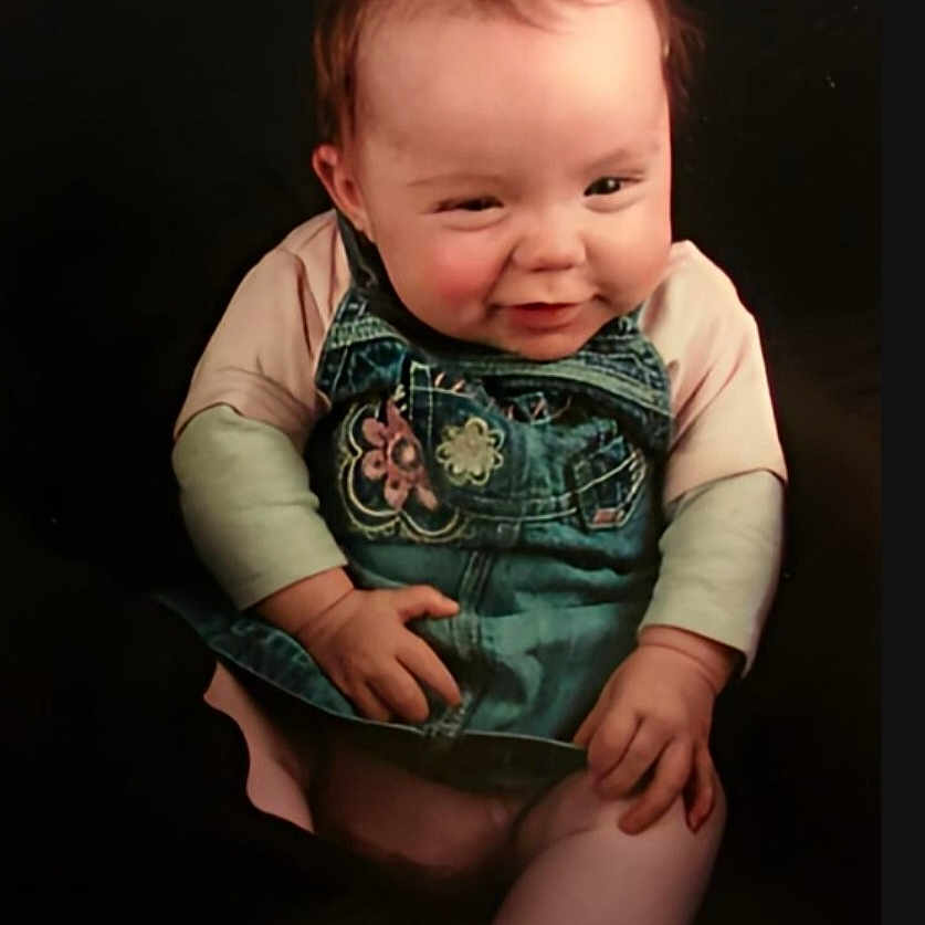 Trinity-Jae joined the competition — help win amazing prizes! baby, background, cheeky, child, clothing, cute, denim, expression, face, hands, infant, long_sleeve, overall, person, pink, portrait, sitting, smile, studio, young