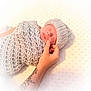 newborn, baby, infant, wrapped, knitted_blanket, knitted_hat, tattoo, hand, sleeping, peaceful, soft_light, cozy, texture, background, skin, portrait, closeup, cute, resting, indoors