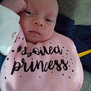 Lena is registered to the contest to win money with this photo: baby, infant, bib, pink, clothing, face, portrait, resting, sleepy, indoor, couch, fabric, hand, person, cute, newborn, young_child, expression, soft, casual