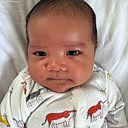 Ronn is registered to the contest to win money with this photo: baby, infant, face, eyes, clothing, onesie, animal_print, blanket, closeup, portrait, cute, child, newborn, skin, expression, head, lying_down, indoors, sleepwear, adorable