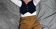 Ronn is registered to the contest to win money with this photo: baby, infant, child, person, clothing, vest, pants, shoes, bed, blanket, lying_down, cute, small_hands, face, indoor, portrait, looking_at_camera, casual_wear, relaxed, young