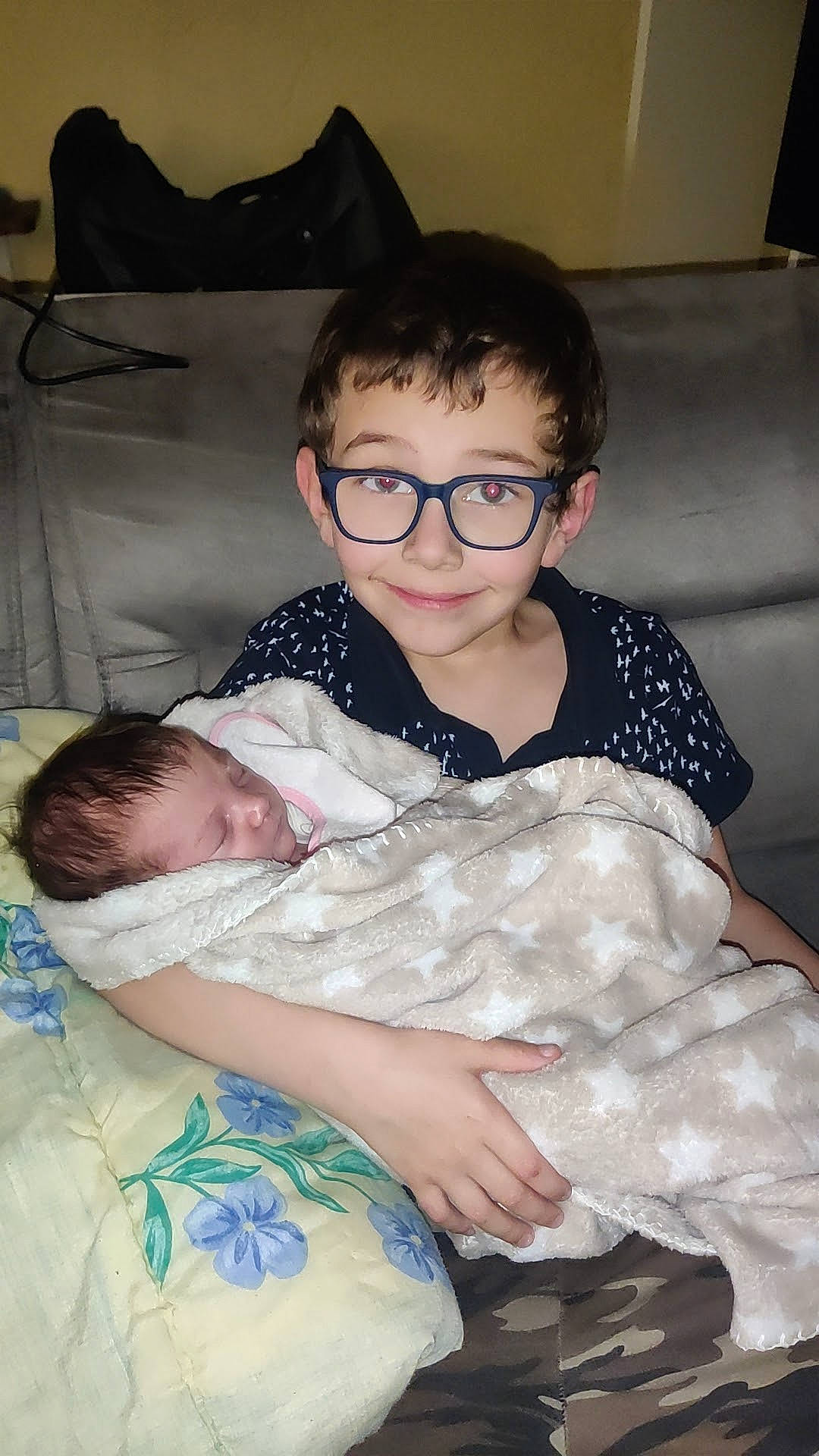 Nohan a rejoint le concours — aidez-le/la à gagner de superbes lots ! baby, baby_toddler_clothing, cheek, child, comfort, couch, event, eyewear, facial_expression, fun, glasses, happy, joy, lap, person, room, sitting, skin, smile, toddler