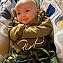 baby, infant, newborn, smile, face, head, eyes, hands, cozy, bouncer, blanket, patterned_blanket, camo_print, clothing, onesie, portrait, indoor, soft_lighting, adorable, relaxed