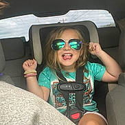Ophelia-Rayne is registered to the contest to win money with this photo: child, car_seat, sunglasses, car_interior, seatbelt, happy, playful, smiling, tongue_out, casual_clothing, bracelets, hair, seat, window, reflection, person, kid, safety, fun, transportation