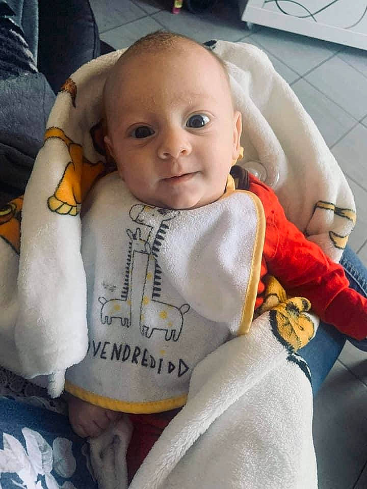 Sacha participe au concours pour gagner de l'argent avec cette photo : baby, baby_carriage, baby_toddler_clothing, bib, car_seat, cheek, comfort, eye, eyebrow, face, happy, head, nose, outerwear, person, product, seat_belt, sleeve, smile, textile