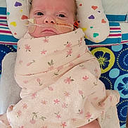 Cora joined the competition — help win amazing prizes! baby, infant, blanket, floral_pattern, hospital, medical_tube, nasal_tube, pillow, heart_pattern, lying_down, swaddled, newborn, leg, foot, medical_tape, bed, colorful, patterned, cute, patient