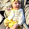 baby, infant, child, blanket, yellow_clothing, headband, face, skin, foot, hand, sitting, soft_texture, cozy, indoors, portrait, cute, newborn, expression, fuzzy, relaxed