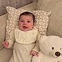 baby, child, comfortable, couch, cozy, cream_outfit, cute, happy, holding, indoors, infant, patterned_pillow, pillow, plush_toy, seated, smiling, soft_texture, teddy_bear, toy, white