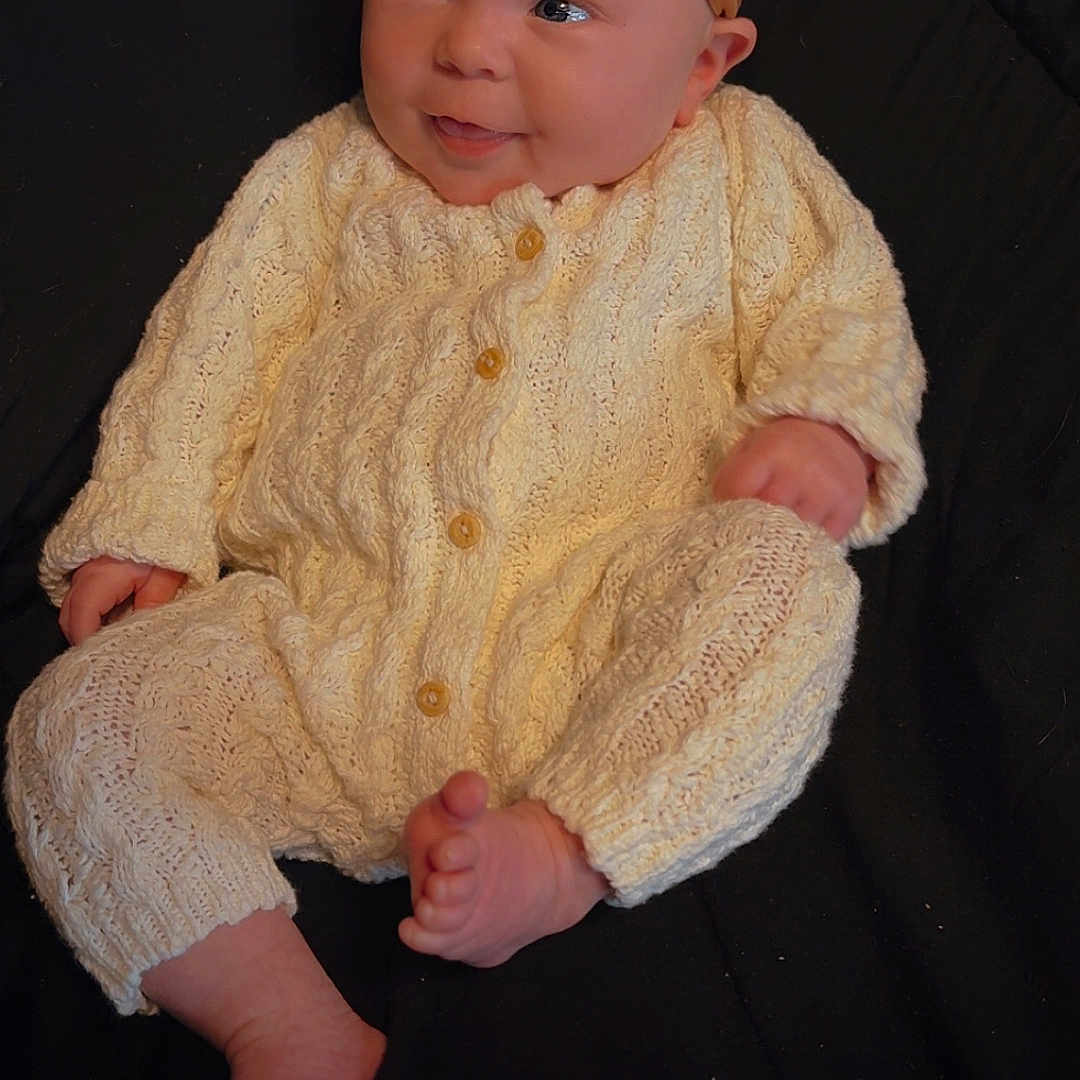 Willow is registered to the contest to win money with this photo: baby, black_background, bow, child, clothing, cute, face, foot, hand, headband, indoors, infant, knitted, laying, newborn, onesie, person, portrait, skin, smiling