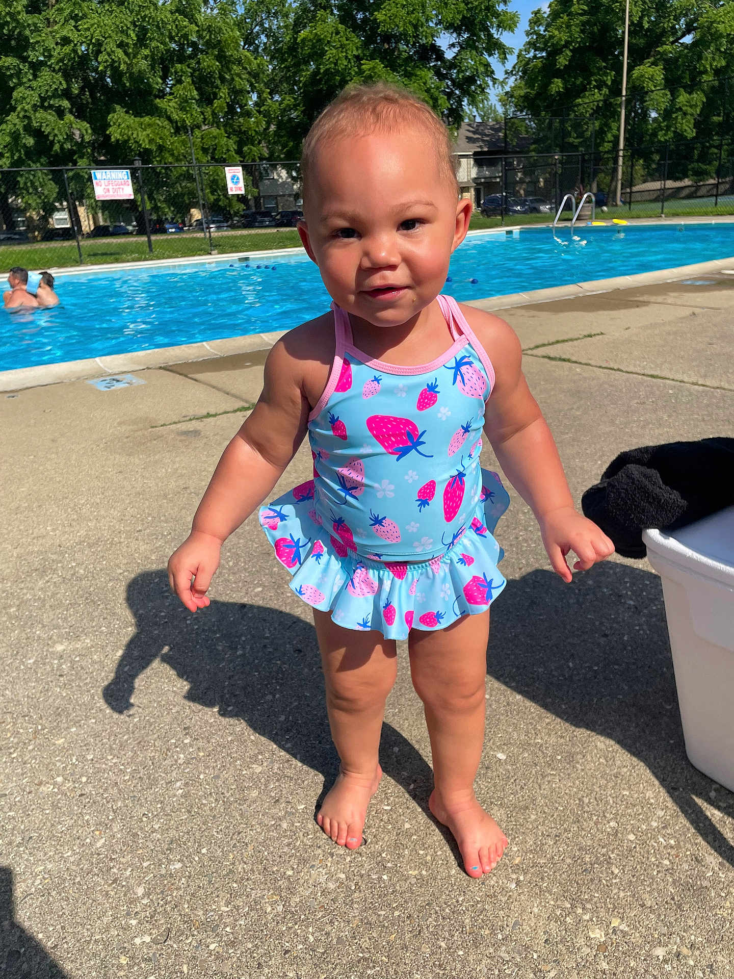 Camyla joined the competition — help win amazing prizes! toddler, child, swimsuit, poolside, concrete, outdoor, summer, sunlight, smile, barefoot, water, trees, fence, shadow, playtime, daytime, young_child, person, blue, pink