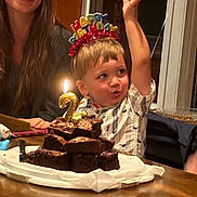 Oliver is registered to the contest to win money with this photo: child, birthday, cake, brownie, candle, happy_birthday_headband, celebration, smiling_woman, table, indoor, party, excited, raising_hand, homemade_cake, food, family, portrait, childrens_party, lighting, fun