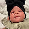 adorable, baby, bedding, black_hat, blanket, bow, cheeks, close_up, clothing, eyes, face, hand, headwrap, indoor, infant, newborn, portrait, ruffle_sleeve, soft_lighting, tiny_hand