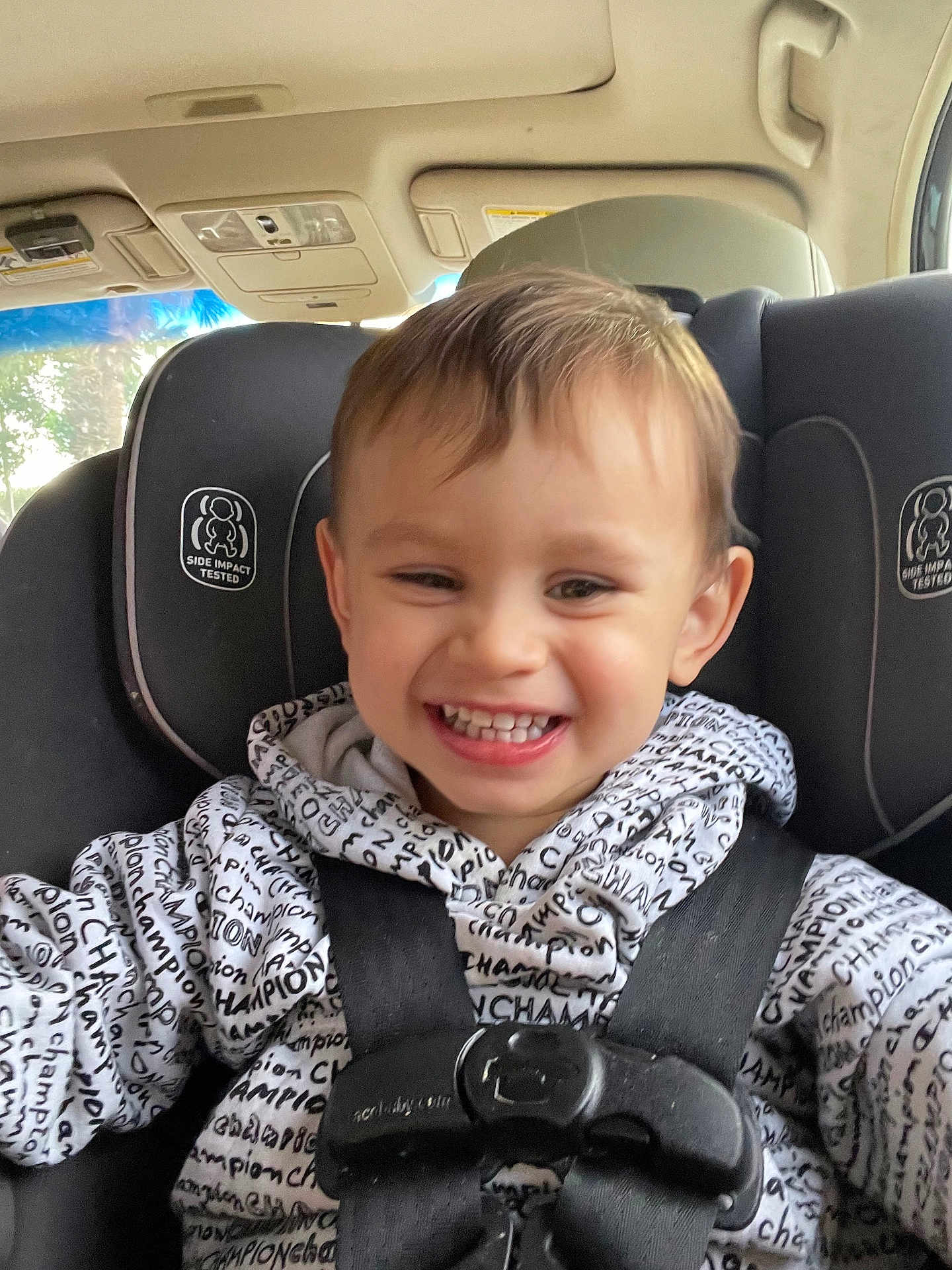 Christopher joined the competition — help win amazing prizes! toddler, child, smiling, car_seat, seatbelt, hoodie, clothing, text_pattern, indoor, car_interior, happy, face, person, young_child, safety, baby, cute, closeup, portrait, seat
