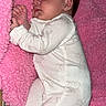 baby, sleeping, blanket, pink, onesie, bunny_pattern, infant, cozy, soft_texture, cute, child, face, hand, footed_pajamas, bed, striped_sheet, resting, peaceful, indoors, portrait