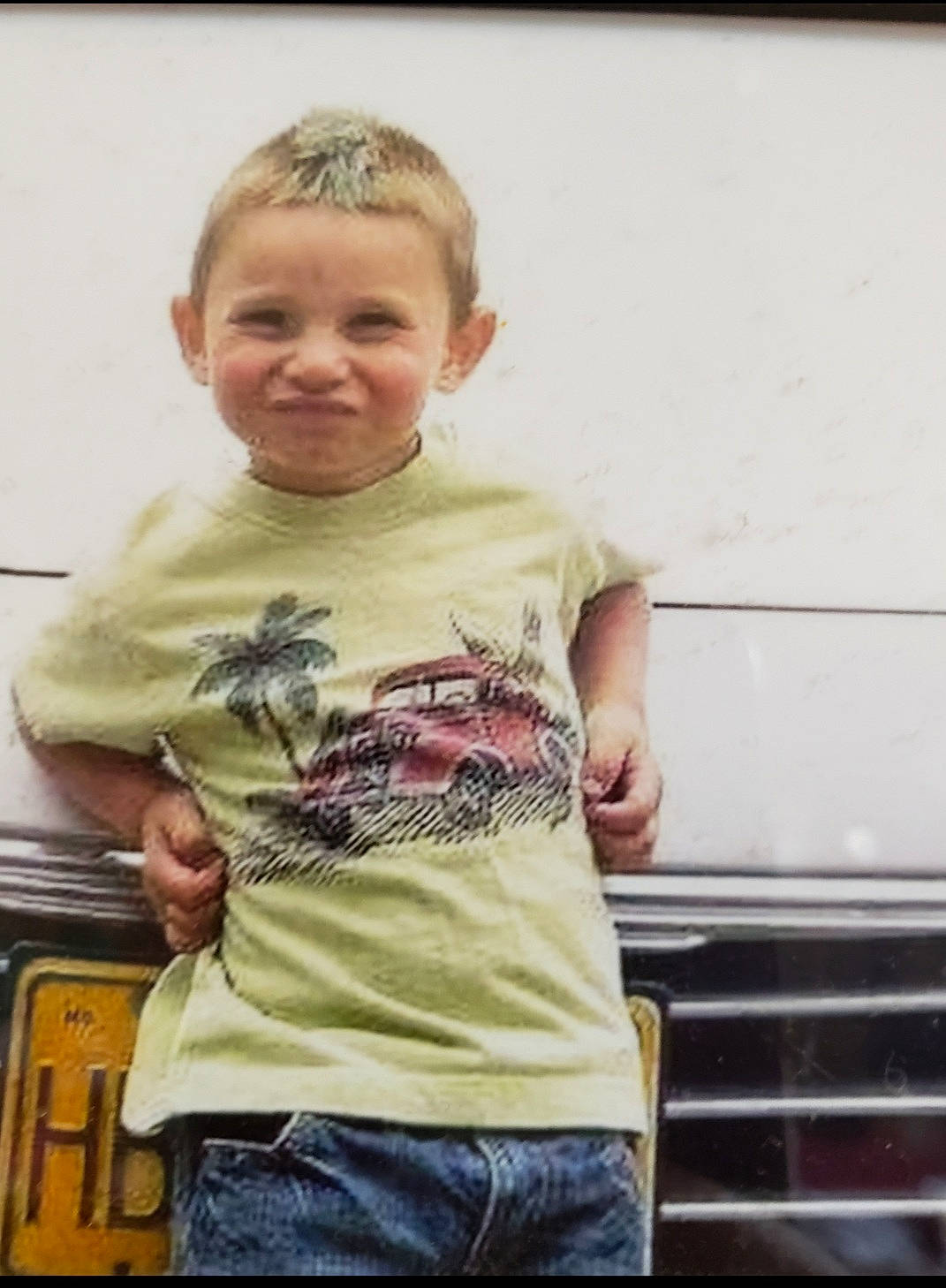 Brody is registered to the contest to win money with this photo: abdomen, automotive_exterior, automotive_lighting, bumper, child, denim, face, fun, hair, hand, happy, head, joy, pattern, person, sitting, sleeve, smile, t_shirt, toddler