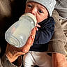 April a rejoint le concours — aidez-le/la à gagner de superbes lots ! baby, bottle, feeding, hand, hat, clothing, person, infant, nail_polish, sitting, warm_colors, closeup, indoors, newborn, sleeve, comfort, feeding_bottle, holding, face, portrait