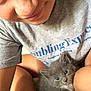 person, kitten, cat, gray_cat, blue_eyes, smiling, selfie, cuddling, indoor, casual_clothing, tshirt, closeup, cute, pet, animal, furry, lap, relaxed, comfort, young