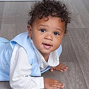 Ryder is registered to the contest to win money with this photo: toddler, child, curly_hair, blue_vest, white_shirt, floor, wooden_floor, portrait, indoor, cute, smiling, hands, baby, crawling, person, young_child, looking_at_camera, curious, face, skin