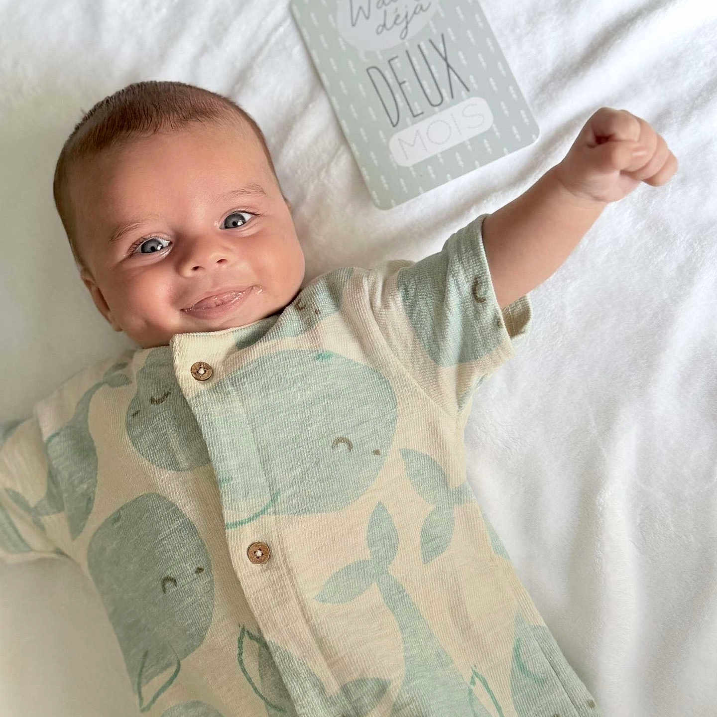 Ioni participe au concours pour gagner de l'argent avec cette photo : baby, blanket, blue_eyes, buttoned_clothing, cheeky, child, cute, happy, indoor, infant, lying_down, milestone_card, onesie, portrait, raised_arm, short_hair, smiling, soft_texture, two_months, whale_pattern