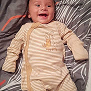 Gino a rejoint le concours — aidez-le/la à gagner de superbes lots ! baby, smiling, onesie, striped_clothing, lying_down, blanket, bed, happy, infant, cute, sleepwear, child, face, head, person, soft_fabric, cozy, indoors, young_child, comfort