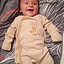 baby, smiling, onesie, striped_clothing, lying_down, blanket, bed, happy, infant, cute, sleepwear, child, face, head, person, soft_fabric, cozy, indoors, young_child, comfort