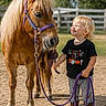 toddler, pony, child, animal, outdoor, smiling, rope, halfter, horse, fence, sunny, daylight, blond_hair, casual_clothing, boots, dirt_ground, pet, farm, cute, friendship