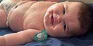 Bryer joined the competition — help win amazing prizes! arm, baby, bed, blue_bedspread, child, chubby, cute, diaper, face, head, indoor, infant, leg, lying_down, pacifier, playful, resting, skin, smiling, wall